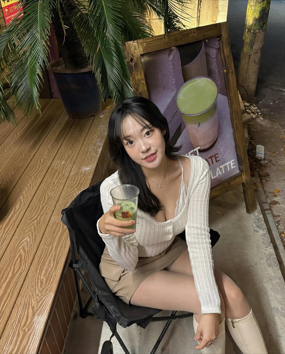 Photo shared by 묘정🐰 on November 10, 2025 tagging @millab.seongsu. May be an image of one or more people, hair, drink, top, deck chair, dress, outdoors and text that says 'CLTES LATTE LATTE'.