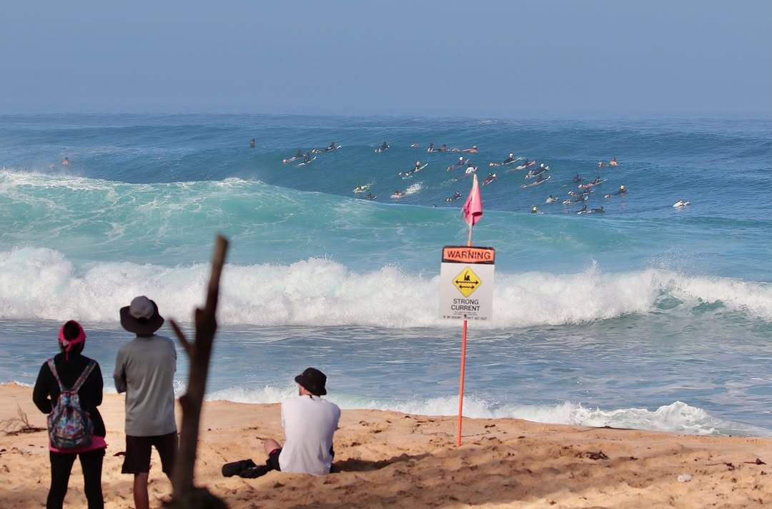 Photo by Pete Hodgson on November 29, 2025. May be an image of surfboard, wetsuit, ocean, beach, water, coast and text that says 'WARNING + CURRENT CURRENT STRONG AOER E 후 タ'.