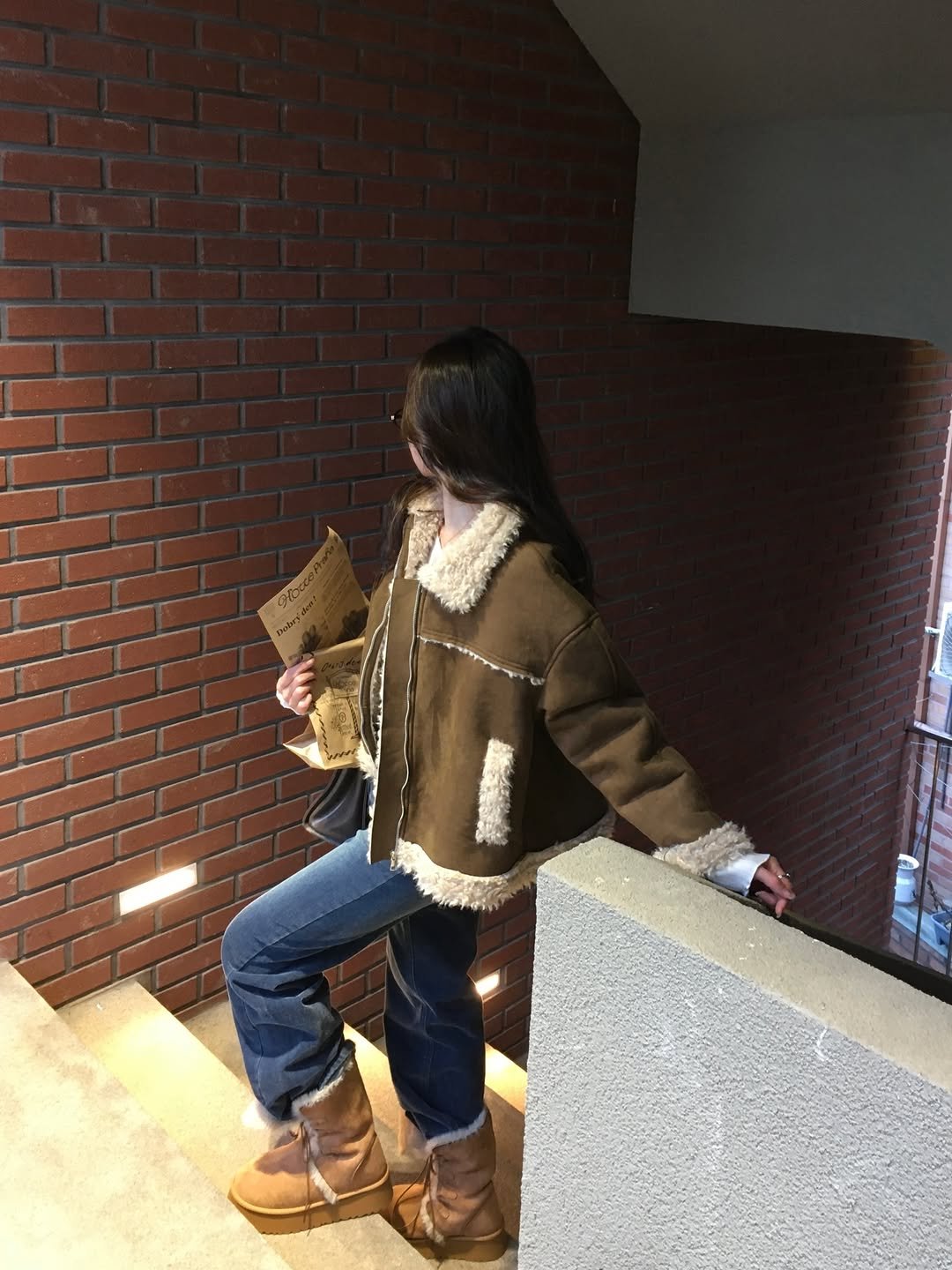 Photo by 포밍뮤즈 on January 11, 2026. May be an image of duffle coat, fur, boots, parka, brick wall and text.