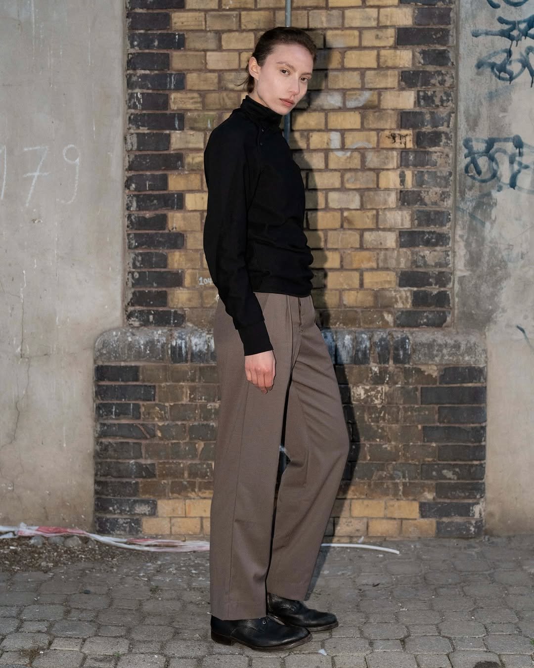 Photo by FÖRMLICH (폼리쉬) on November 10, 2025. May be an image of turtleneck, brick wall and text.