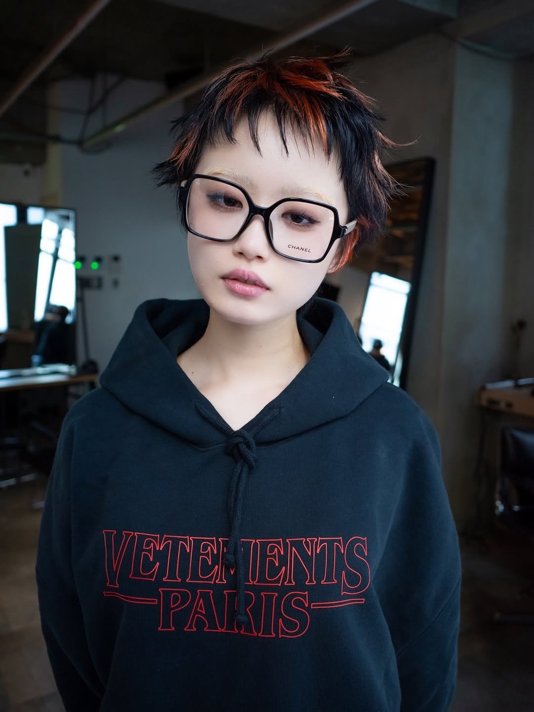 Photo shared by TOMO 渋谷 美容師  ハイトーン/ボブ 矢崎友也 on December 07, 2025 tagging @geeks_shibuya. May be an image of one or more people, braids, duffle coat, eyeglasses, eye patch, sweatshirt and text that says 'EMANEI ETEI IENTS PAI PARIS RIS'.