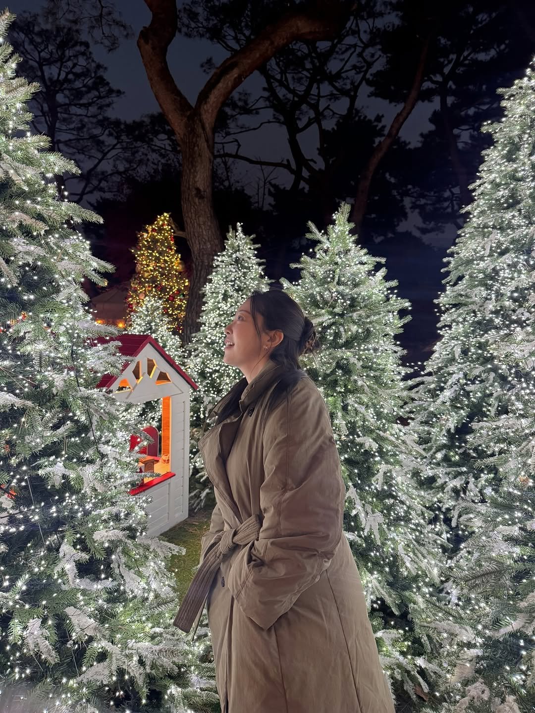 Photo by 김가은 on December 25, 2025. May be an image of duffle coat, overcoat, christmas tree, parka, tinsel, night and text.