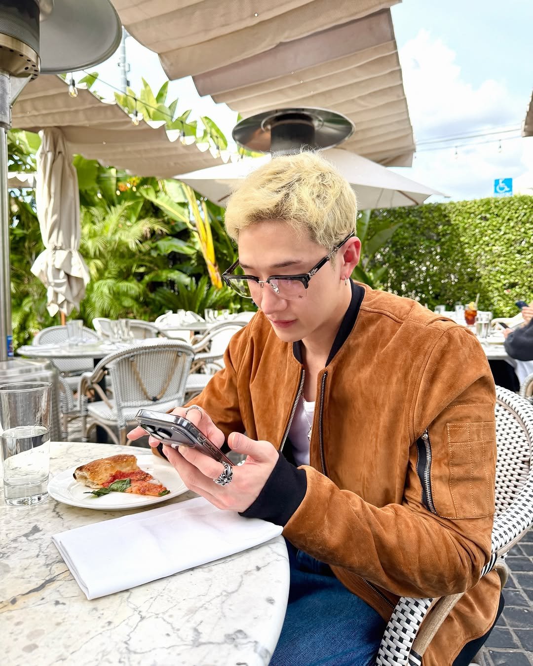 Photo by Bang Chan on February 14, 2026. May be an image of phone, eyewear, jacket and text.