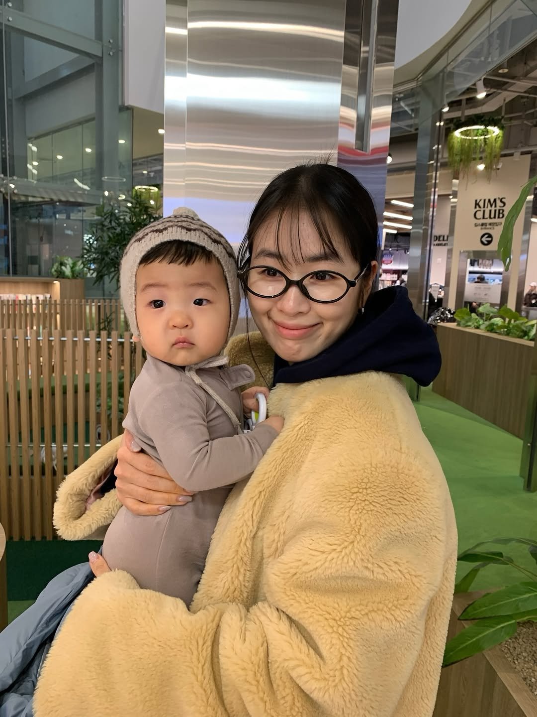 Photo by GOONIINI💚 on February 25, 2026. May be an image of baby, duffle coat, sling, parka and text.