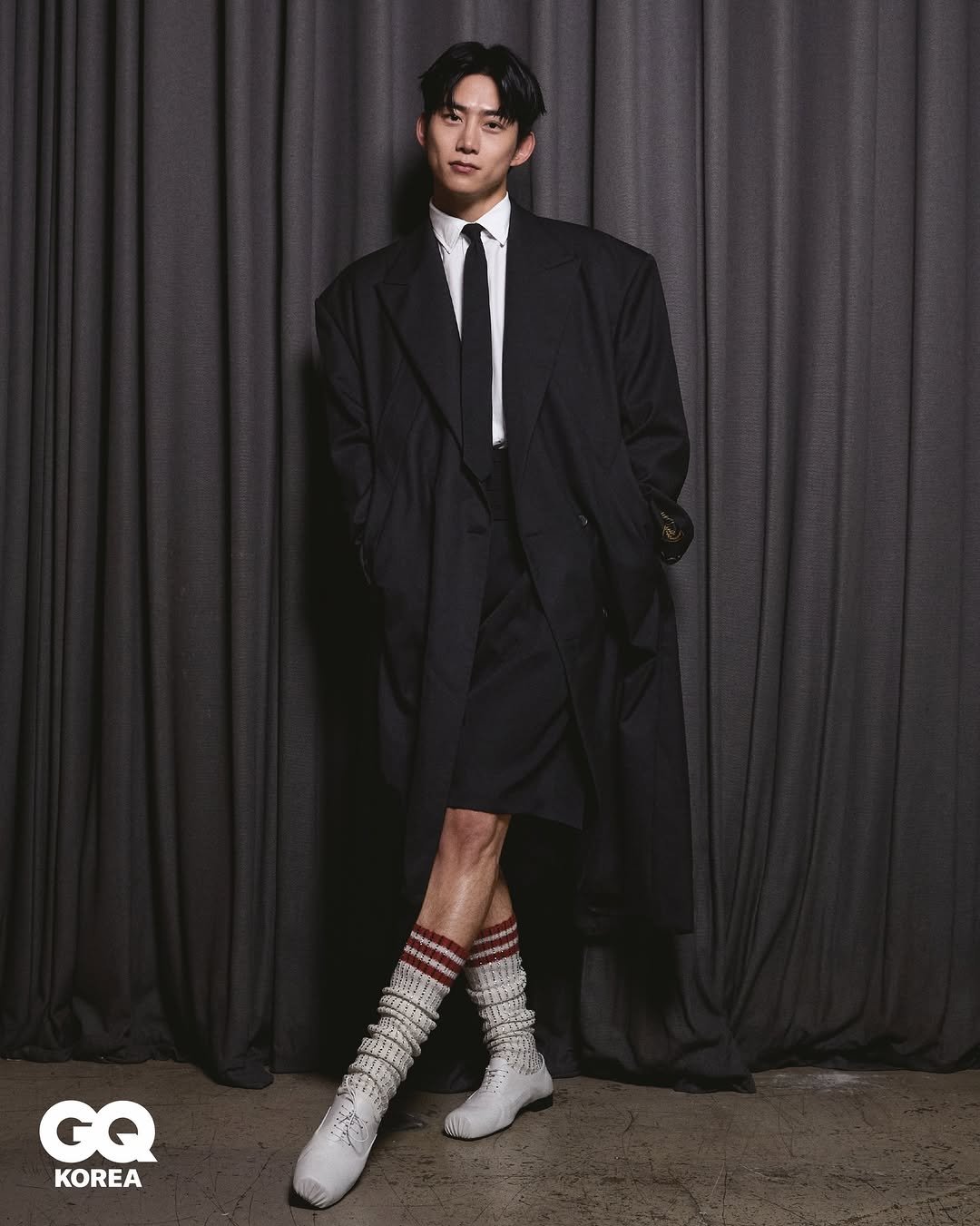 Photo shared by GQ KOREA on April 26, 2026 tagging @taecyeonokay. May be an image of duffle coat, overcoat, suit, wingtip shoes, bolo tie, kilt and text.