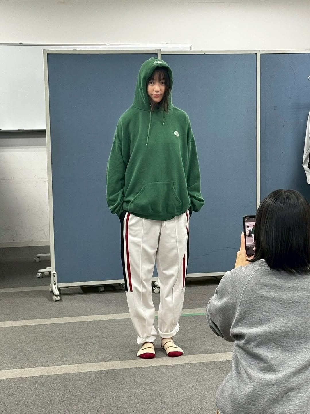 Photo by Hanhyojoo on October 17, 2025. May be an image of one or more people, bangs, people standing, sweatpants, fleece, sportswear, parka, cloak, turtleneck and text.