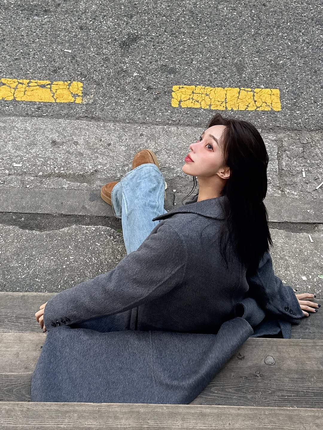 Photo shared by 정혜리 on November 28, 2025 tagging @ririnco_official. May be an image of one or more people, overcoat, duffle coat, boots, road, street, curb and text.