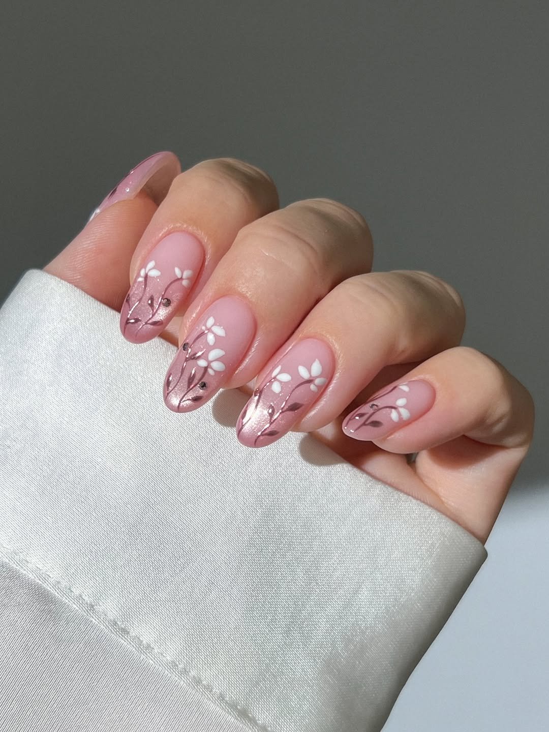 Glassy pink ombre nails with pink chrome and white flowers, milky pink nails spring nails, shimmery nails, sparkly nails, dainty gold pearl ring, curved diamond wedding ring, dainty gold eternity ring, pastel pink blue aura nails with 3D yellow flowers and ladybugs, polka dot nails, French tip nails, gold open leaf ring with diamonds, gold dotted ring, pastel blue and yellow nails, blueberry nails, daisy flower nails, summer nails, cottage core nails, lace nails, picnic nails, bow nails,