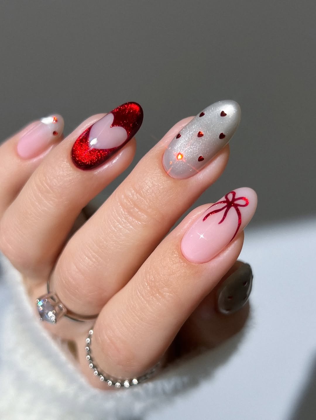 Red velvet heart nails, Valentine’s Day nails, silver nails, white nails, polka dot nails, bow nails, French tip nails, pink nude nails, silver heart gem ring, silver dotted ring, Blue nails, glass nails, winter nails, cat eye gel nails, icy heart nails, sparkly snowflake nails, magnetic heart nails, silver marquise cut eternity ring, ruby crystal nails, cut out heart nails, silver glitter nails, classy vday nails, silver dangling heart ring,