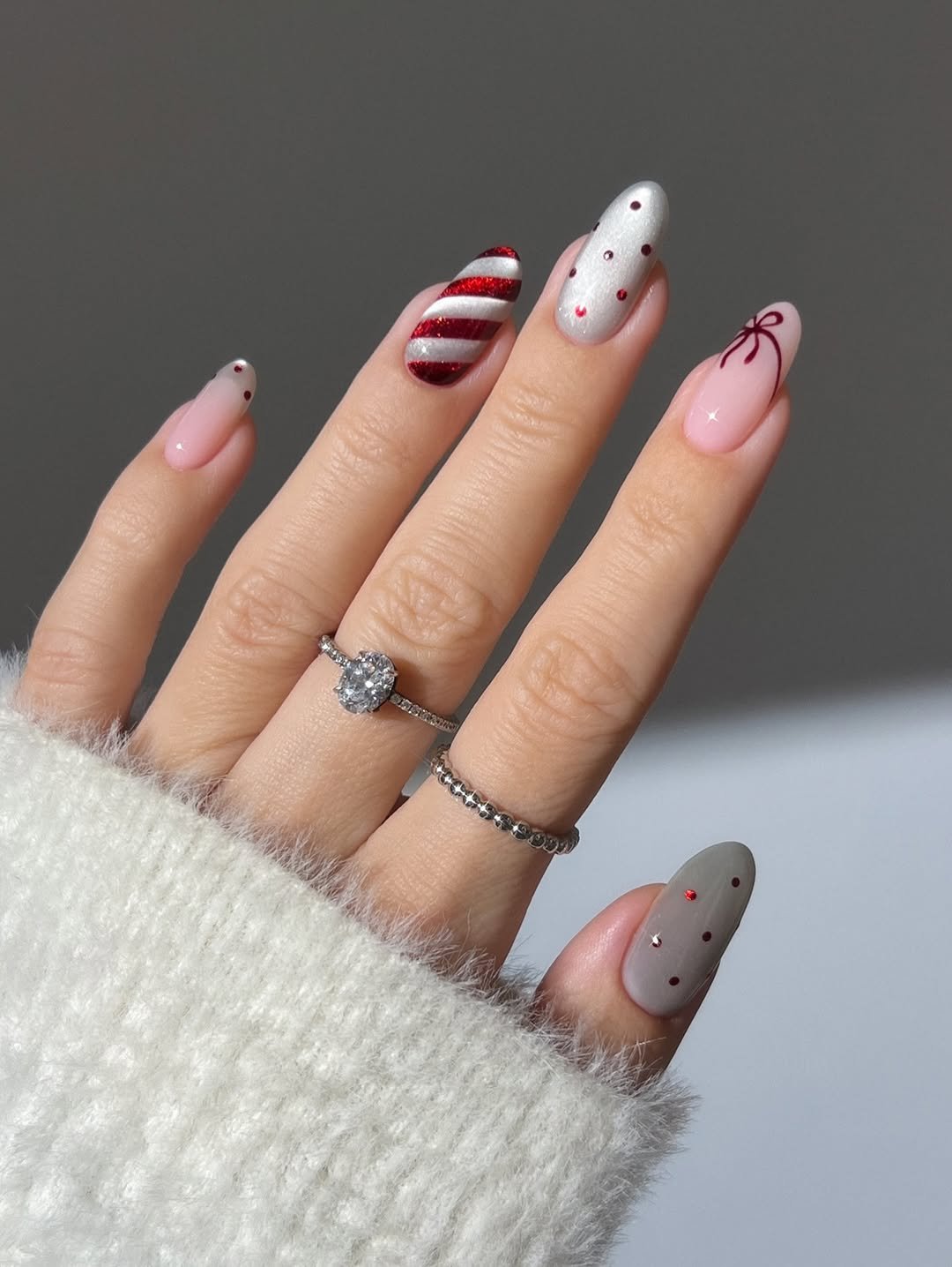 Mix and match candy cane nails, polka dot nails, red nails, white nails, silver nails, cat eye nails, Christmas nails, holiday nails, French tip mails, bow nails, ribbon nails, glass nails, velvet nails, silver oval diamond ring, silver dotted ring, Green nails, emerald nails, xmas tree nails, textured nails, gold dome ring with oval emerald, almond nails, deep red bow nails, sparkly nails, glitter nails, snowflake nails, marquise cut silver eternity ring ,