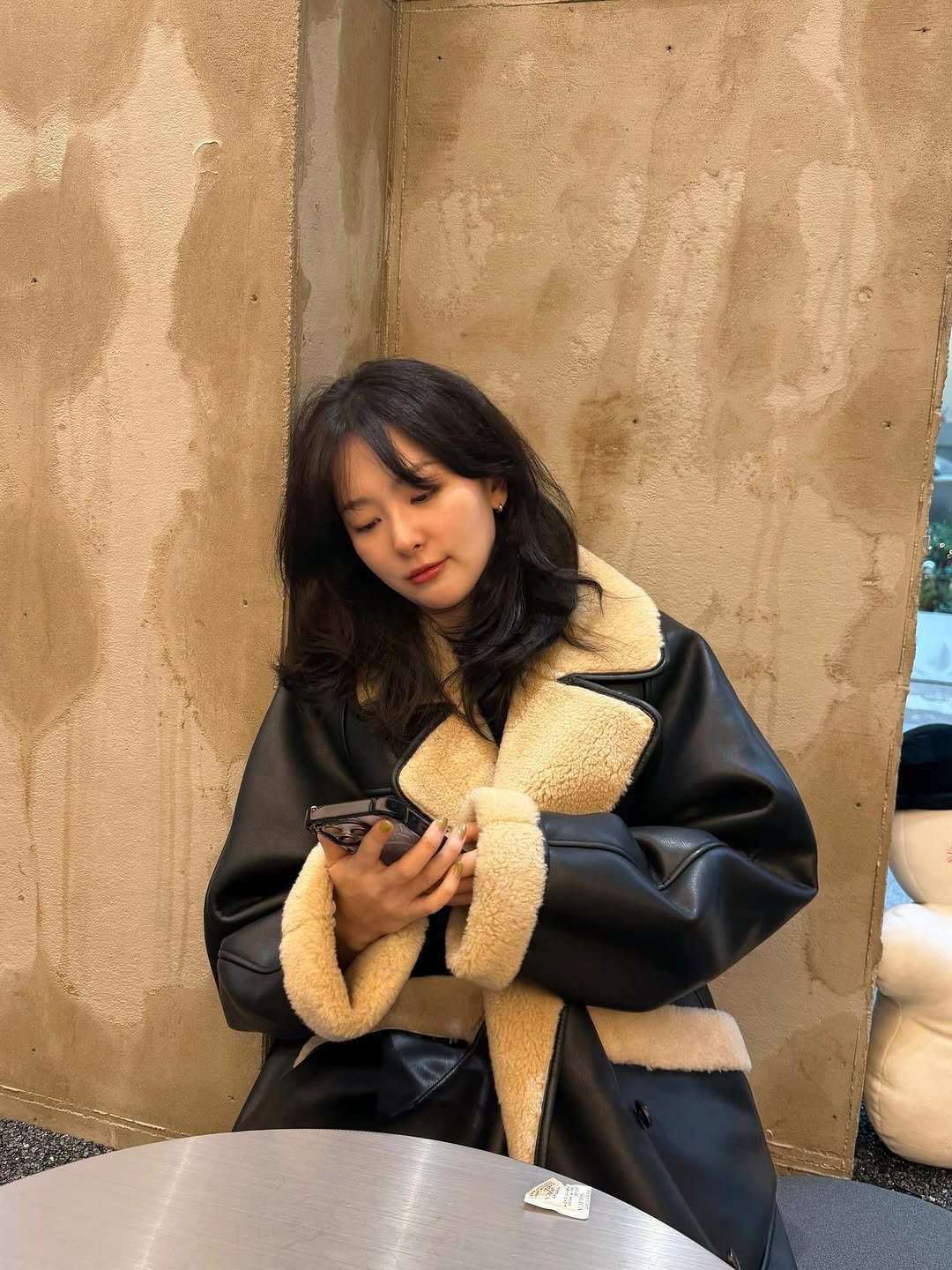 Photo by 슬기 Seulgi on December 02, 2025. May be an image of one or more people, hair, duffle coat, overcoat, phone, goosedown coat, jacket, turtleneck, parka, cornflower and text.