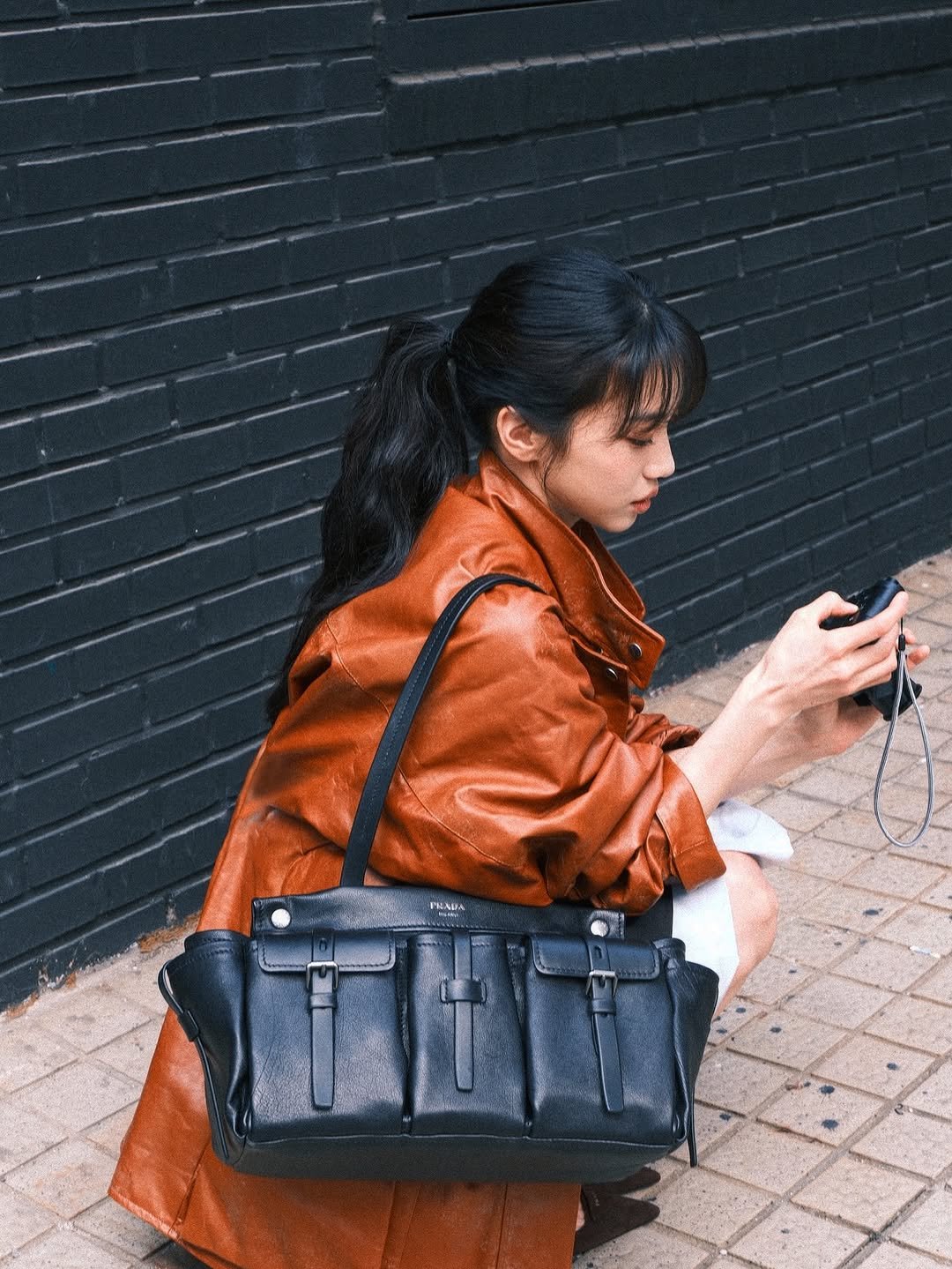 Photo shared by 홍화연 ••• Hong Hwayeon on March 23, 2026 tagging @prada. May be an image of phone, leather, saddle-stitched leather, briefcase, purse and text.