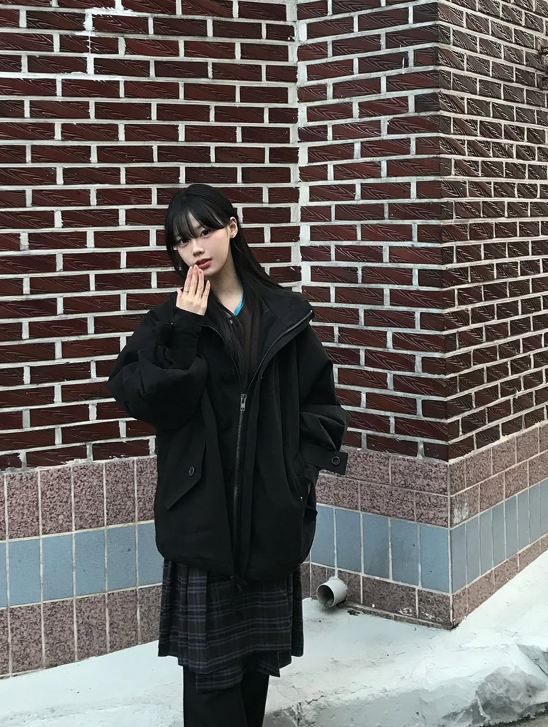 Photo shared by 뭐혜연 on December 21, 2025 tagging @sio.seoul. May be an image of smoking, duffle coat, overcoat, jacket, turtleneck, parka, brick wall and text.