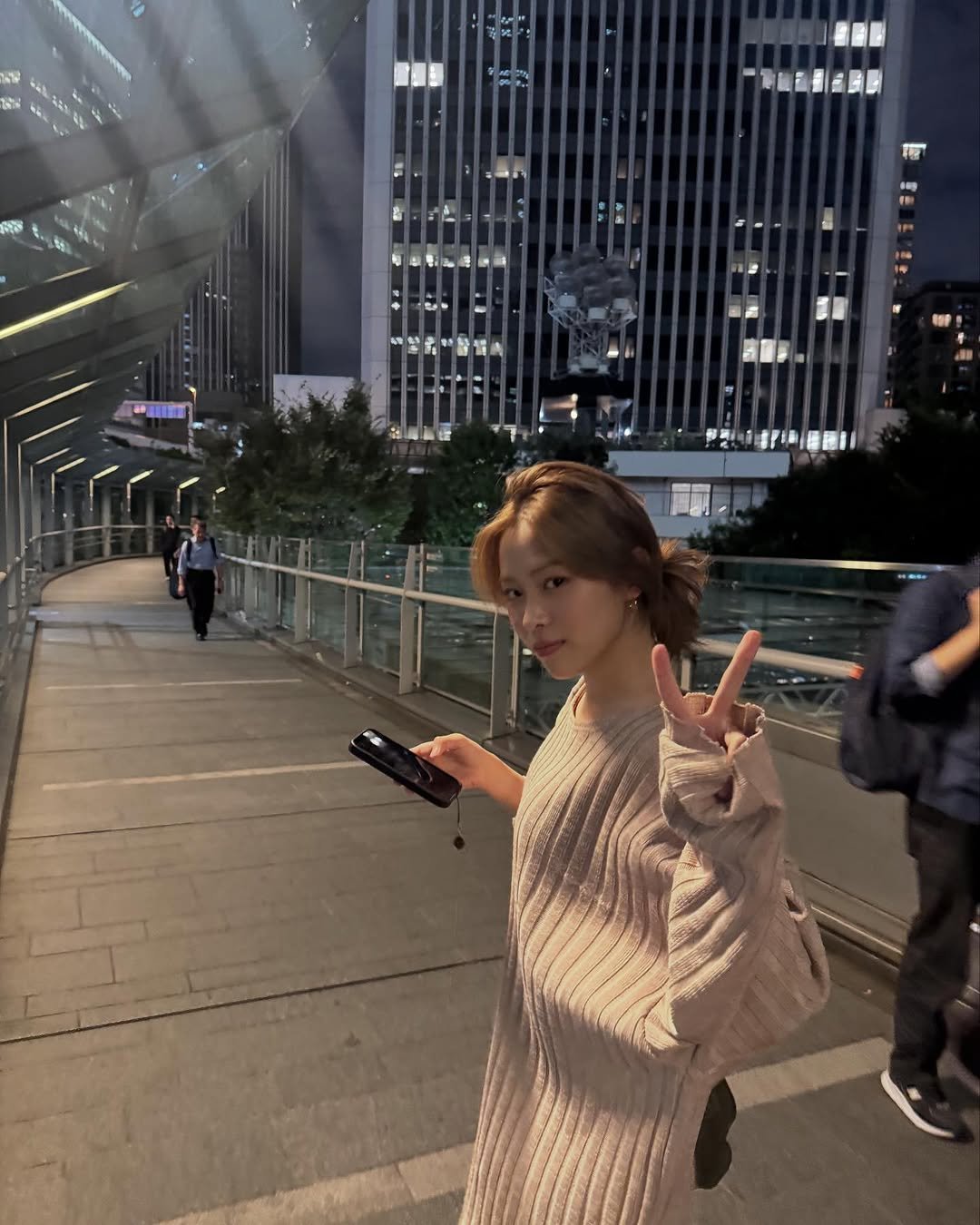 Photo by RYUJIN on October 16, 2025. May be an image of one or more people, hair, turtleneck, skyscraper, Victoria Peak, night and text.