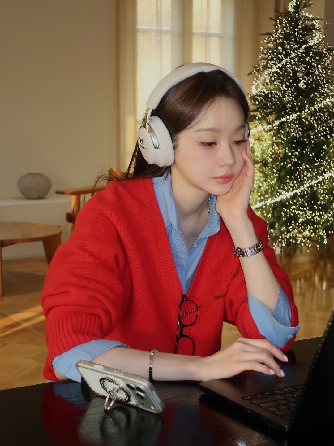 Photo shared by 강민경 (행동파) on December 18, 2025 tagging @bose. May be an image of studying, phone, sweater, tablet, computer keyboard, portable cassette player and text.