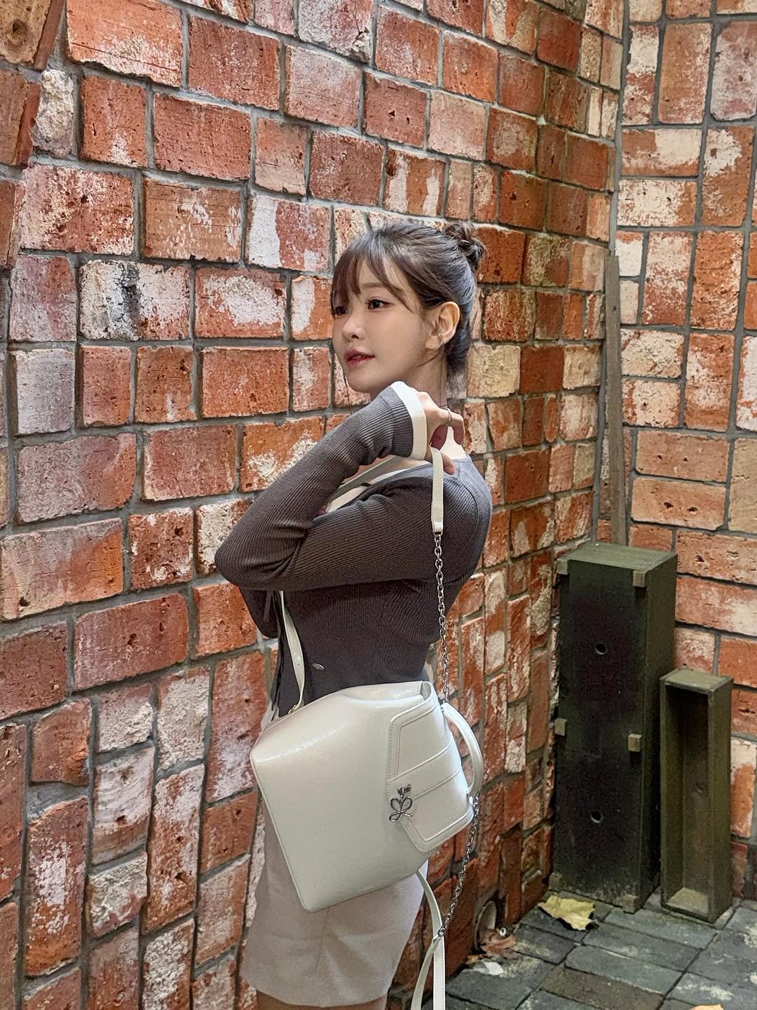 Photo shared by 김윤희 아나운서 on September 22, 2025 tagging @generalidea_official. May be an image of 1 person, purse, brick wall and text.