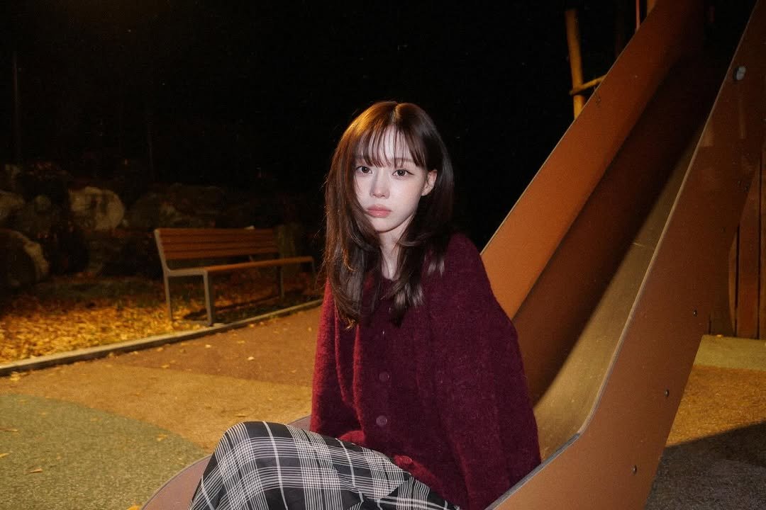 Photo by WINTER on December 26, 2025. May be an image of one or more people, makeup, hair, duffle coat, turtleneck, park and text.