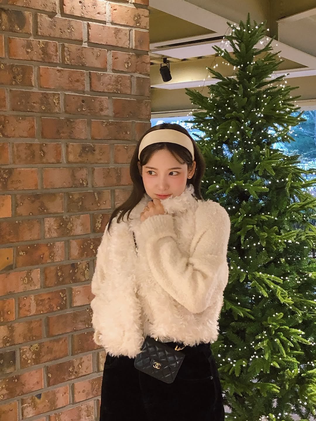 Photo by 이나연 on December 21, 2025. May be an image of one or more people, hair, duffle coat, christmas tree, fur, beret, parka and text.