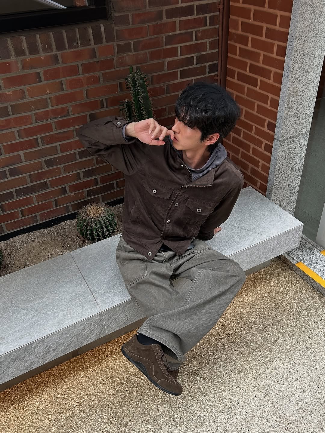 Photo by 정재훈 | CAON on September 12, 2025. May be an image of 1 person, smoking, wingtip shoes, duffle coat, cigarette, brick wall, curb and text.