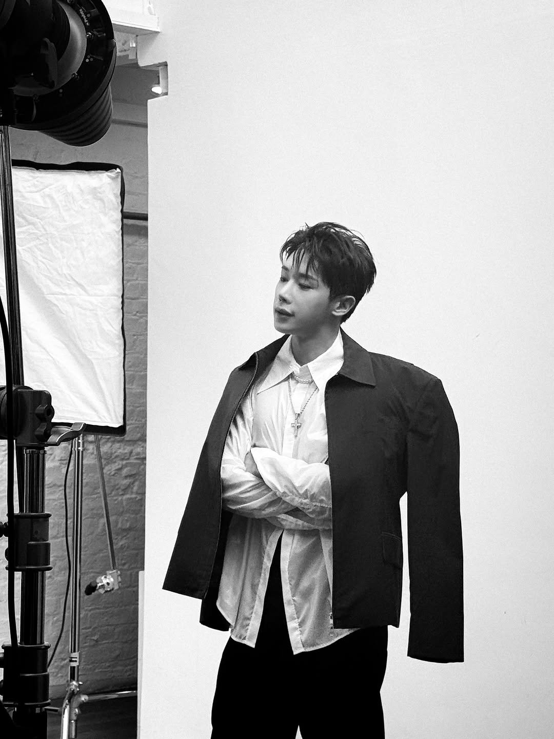 Photo shared by WONHO official on November 28, 2025 tagging @iwonhoyou. May be a black-and-white image of one or more people, overcoat, cloak, bolo tie, suit, blazer and text.