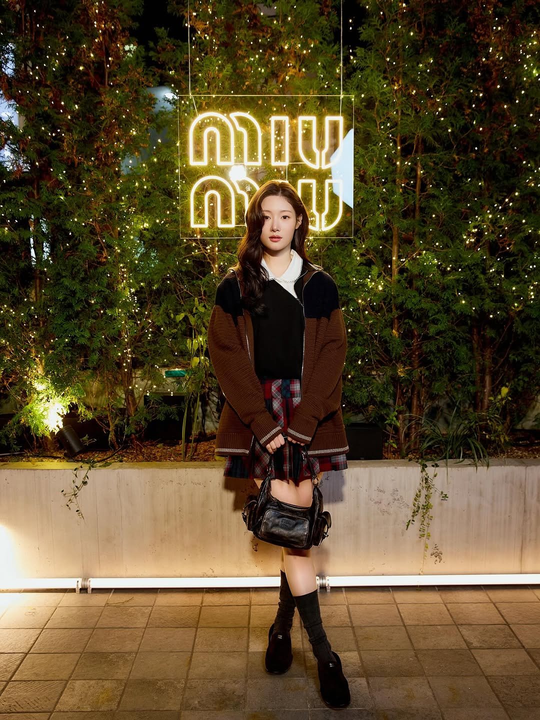 Photo shared by 정채연 on November 12, 2025 tagging @miumiu. May be an image of duffle coat, overcoat, miniskirt, outdoors and text.
