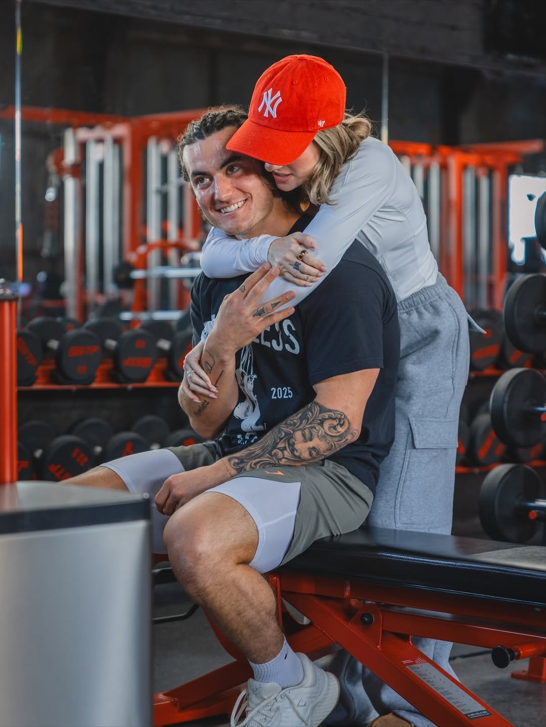 Photo shared by Jesse James West on November 23, 2025 tagging @claudiamariewalsh, @phil_bitar, and @relentlessusa.shop. May be an image of one or more people, biceps, people smiling, people kissing, sportswear, barbell and text.