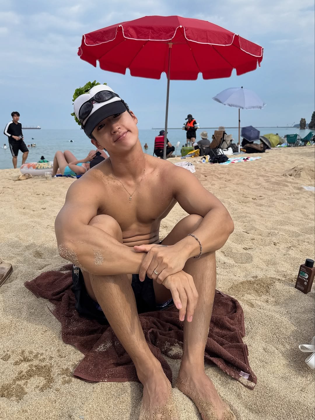 Photo by 지상근 / JIDAOL(지다올) on September 05, 2025. May be an image of 2 people, biceps, people bodybuilding, hat, umbrella, beach, ocean and text.