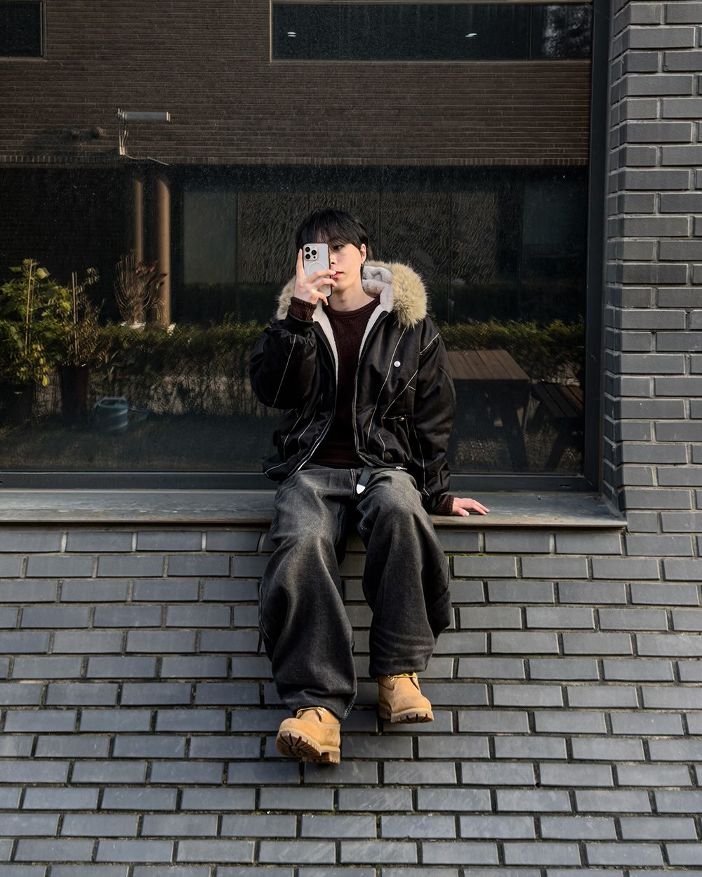 Photo by 지금JIIGEUM❄️ on December 07, 2025. May be an image of smoking, duffle coat, cigar, cigarette, parka, street, brick wall and text.