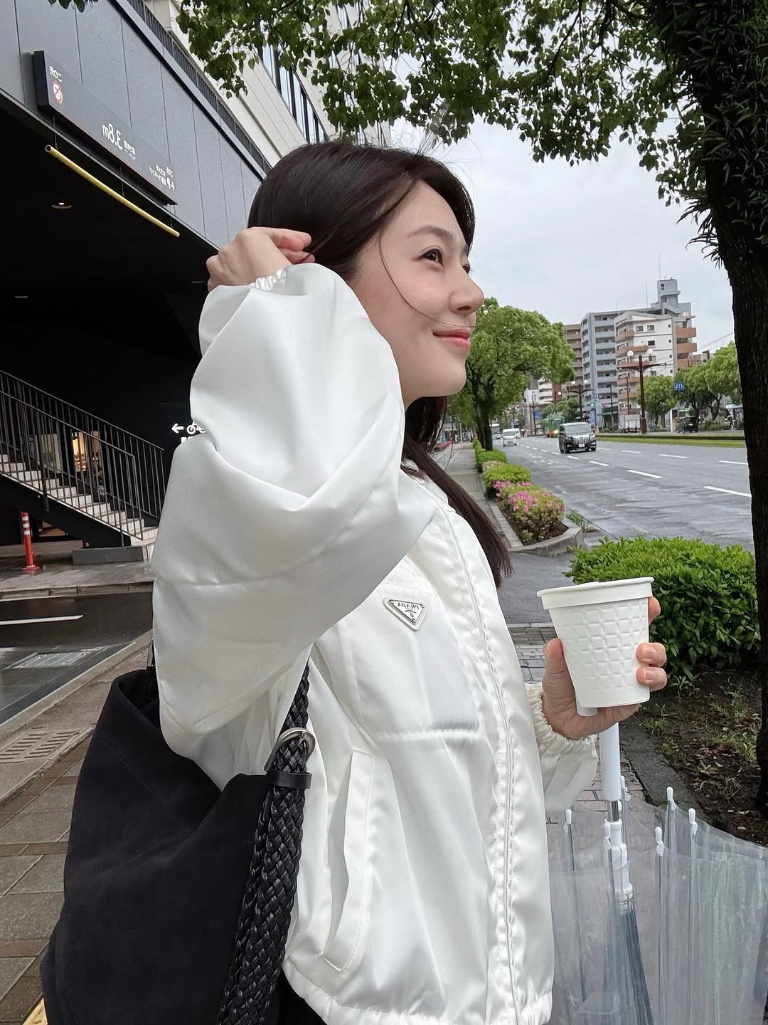 Photo shared by Baek jinhee💕 on April 13, 2026 tagging @prada, and @ttam__official. May be an image of overcoat, parka, jacket, raincoat, cornflower, white lily and text.