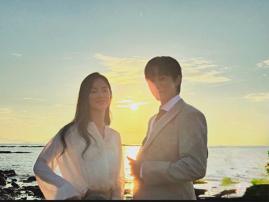 Photo shared by b1a4 jinyoung on November 04, 2025 tagging @jeon.yeobeen. May be an image of one or more people, suit, dinner jacket, barong, wedding, twilight, beach and text.