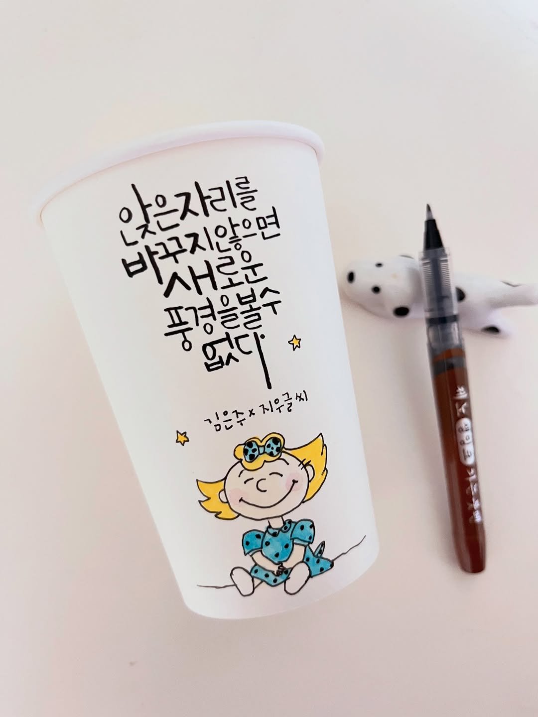 Photo by 신지우캘리그라피/지우글씨 on December 26, 2025. May be an illustration of coffee cup and text that says '앉은자리를 바꾸지않으면 새로운 푸경을불수 ይለር 김은주* 김은주*지우글씨 व'.
