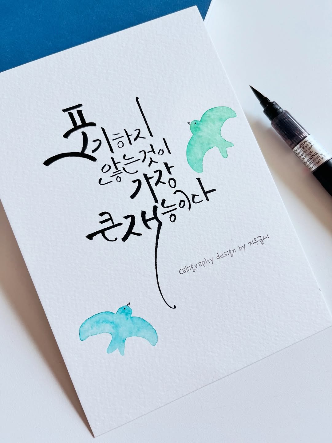 Photo by 신지우캘리그라피/지우글씨 on April 27, 2026. May be a doodle of dolphin, pen, card and text that says 'ព៉ម 포키지 않는것이 근재능이다 フストス・ Caltgraphy deston by 지우글씨'.