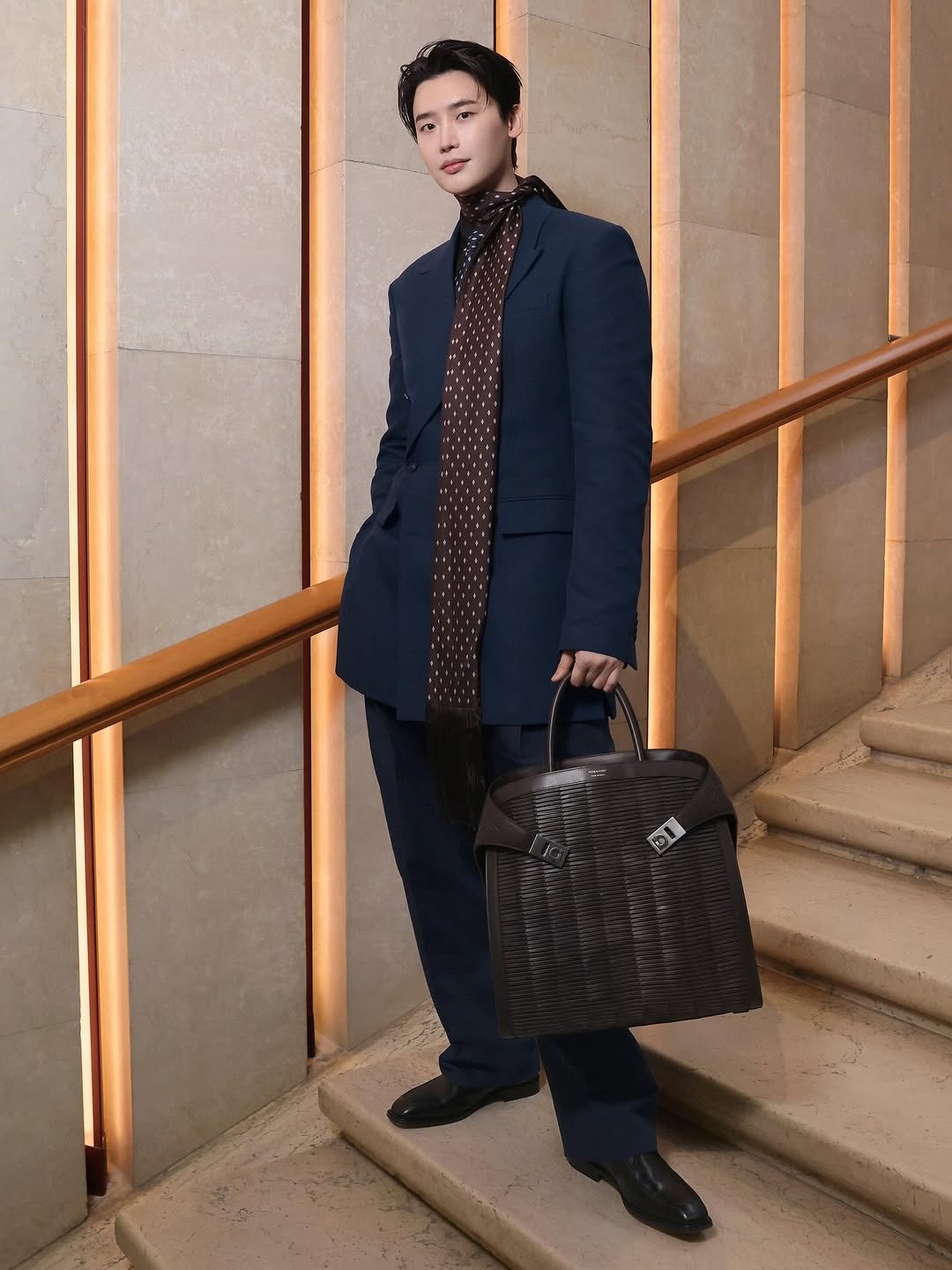 Photo shared by FERRAGAMO on March 01, 2026 tagging @jongsuk0206. May be an image of overcoat, blazer, briefcase, suit, purse and text.