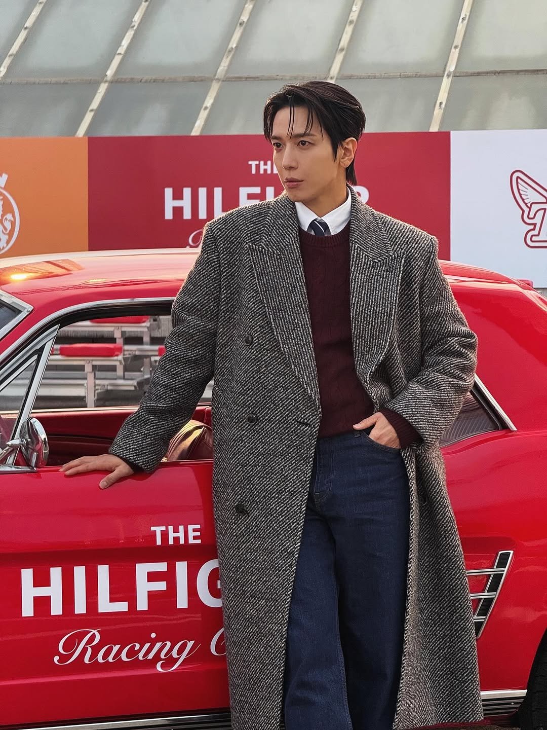 Photo shared by 정용화 on October 28, 2025 tagging @tommyhilfiger. May be an image of duffle coat, overcoat, goosedown coat, turtleneck, fur, bolo tie and text that says 'Η HILEI - T THE HILFIC Racing'.