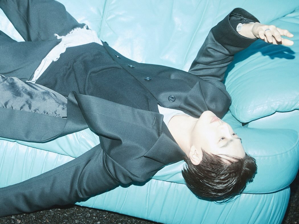 Photo by SUHO on September 22, 2025. May be an image of one or more people, bangs, top, beanbag chair and bolo tie.