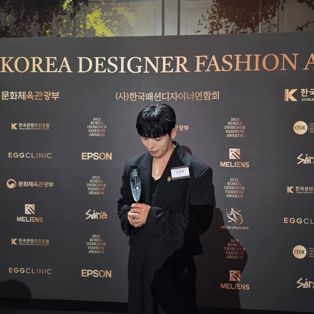 Photo by Daeheon Kang on November 28, 2025. May be an image of overcoat, bolo tie, top and text that says '문화체육관광부 DESIGNER EADESIGNERFASH FASHION 한국콘텐츠진흥원 (사)한국패션디자이너연합회 KOREA चवमर FASHION AWARD 한국 KORE 2025 사광부 EGGCLINIC DESIGN AWARDS EPSON CFDK 문화체육관광부 ΚΟЖИ DESIGNE FASHION AWARDS 대래인 に MELIENS N MELIENS SAn 2025 DESECN KORLA FASHT BASU GNEE AWARD SAnA K 한국콘텐 한국콘텐츠진흥원 원 한국콘텐 2025 KORE DESIGN AWARL ESSLPSEDOMN EGGCLI IC EGGCI EPSON ON CFDK R MELIENS SAN'.