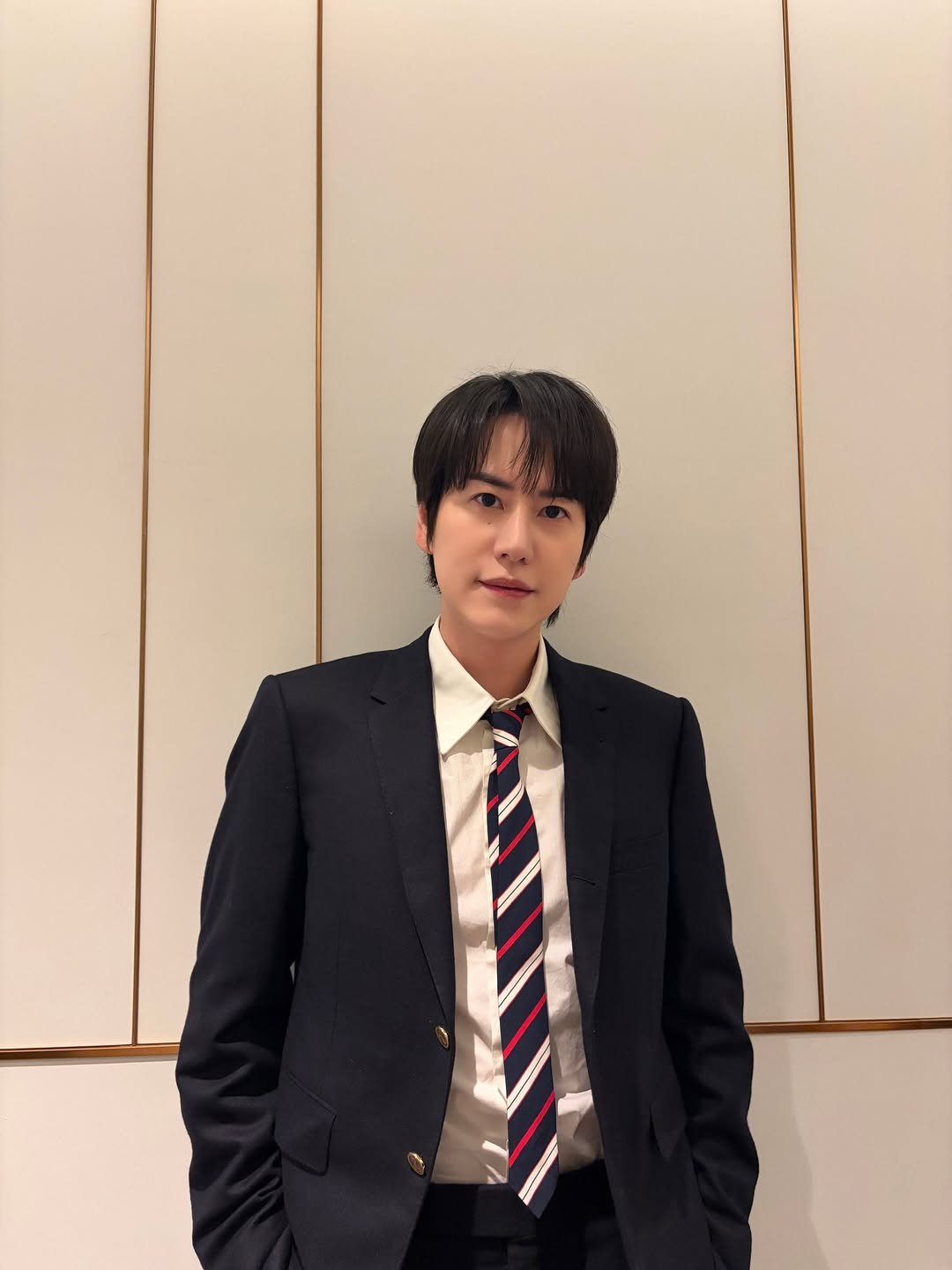 Photo shared by 규현 KYUHYUN on February 05, 2026 tagging @gyuram88. May be an image of blazer, bolo tie, suit and text.