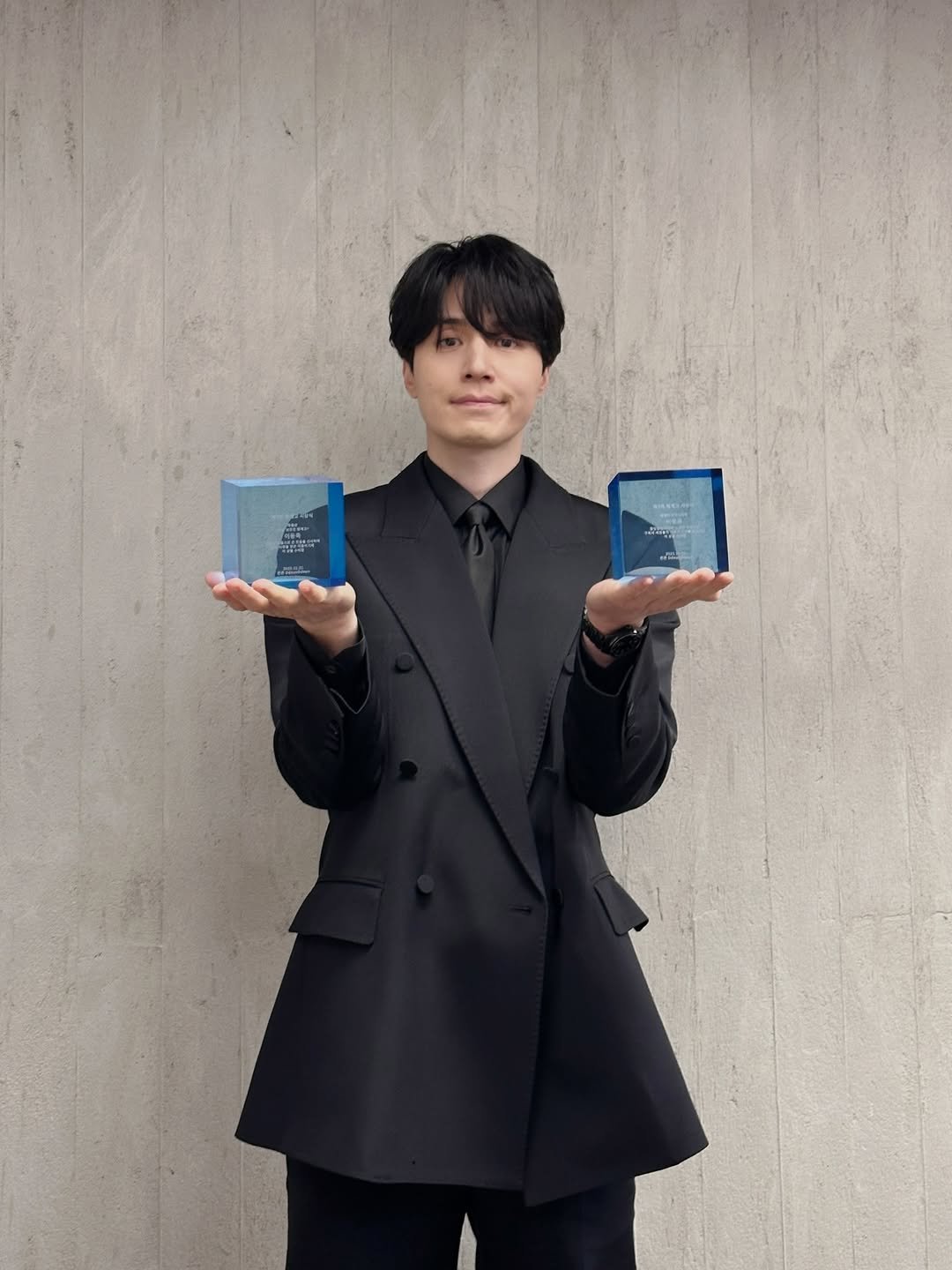 Photo by 이동욱 (Official_Instagram) on December 20, 2025. May be an image of duffle coat, phone, overcoat, blazer and suit.