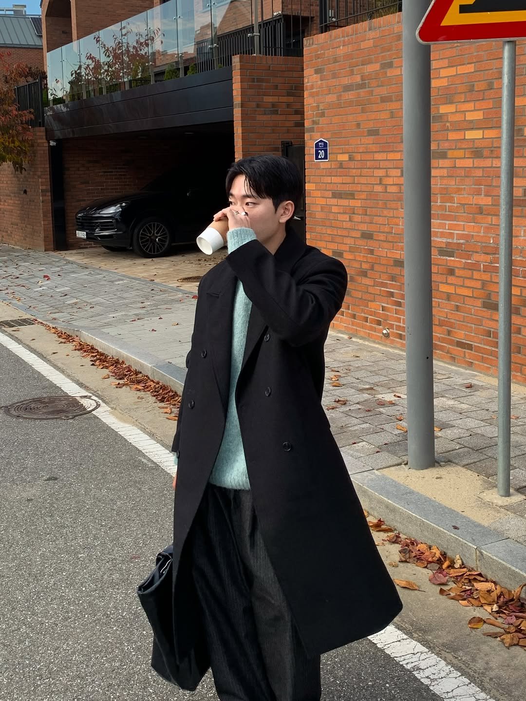 Photo by 르니던 on November 27, 2025. May be an image of duffle coat, overcoat, cigarette, parka, suit, cornflower, street and text.