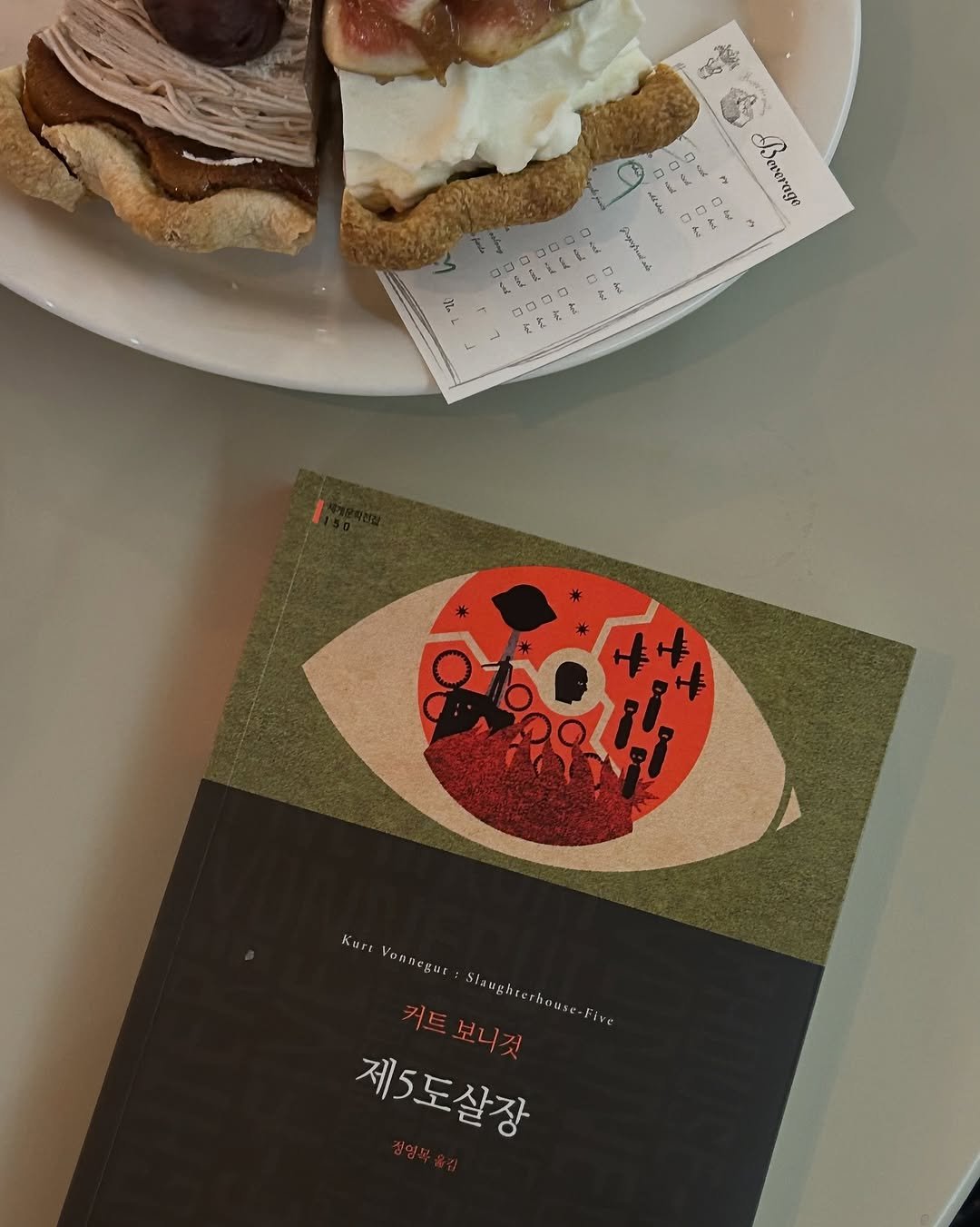 Photo shared by 혜리 on September 25, 2025 tagging @munhakdongne. May be an image of tart, cake, pie and text that says 'Severage 300000 300 0 Kure Von Yonnegura Staughserhouse. fire Siaughr 커트보니 커트 보니것 riouse 제5도살장'.