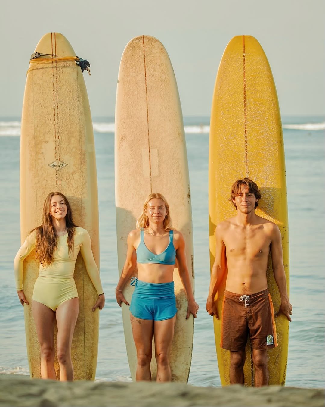 Photo shared by Longboard surf retreats on November 18, 2025 tagging @whine.sap, @dan_pascacio, and @bria5s. May be an image of surfboard, wetsuit, water, beach and text.