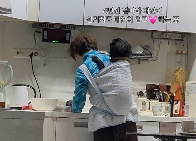Photo by 유튜브채널: 견생대박태안이네 on August 03, 2025. May be an image of 1 person, sling, pot, pie, cooker and text that says '6년진 엄마와 태안이 설거지도 태안이 업고 하는 중'.