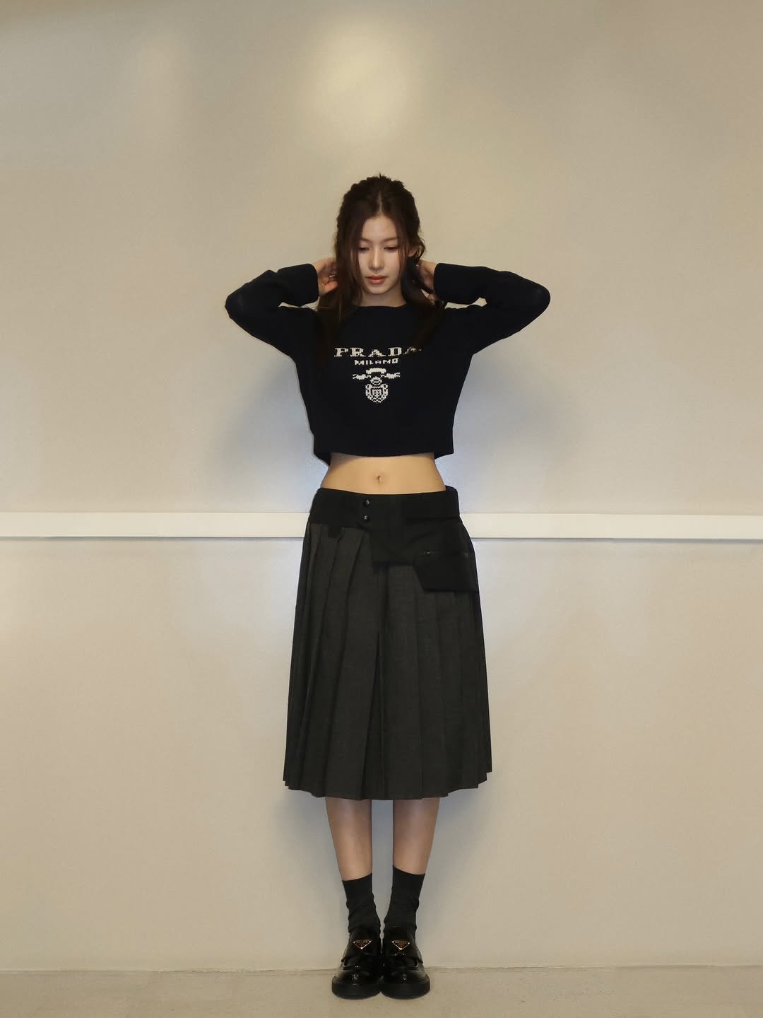 Photo shared by 사나 𝚂𝚊𝚗𝚊 on December 04, 2025 tagging @prada. May be an image of turtleneck, kilt, miniskirt, skirt, top and text.