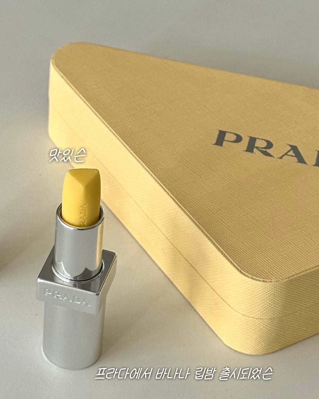 Photo shared by 🥇뷰티계의 트랜드세터 #상은언니 on September 29, 2025 tagging @prada, and @pradabeauty. May be an image of one or more people, lipstick, makeup, cosmetics and text that says '맛있슨 PRA 프라다에서 바나나 립밤 프라다에서바나나립밤출시되었슨 출시, 출시되었슨'.