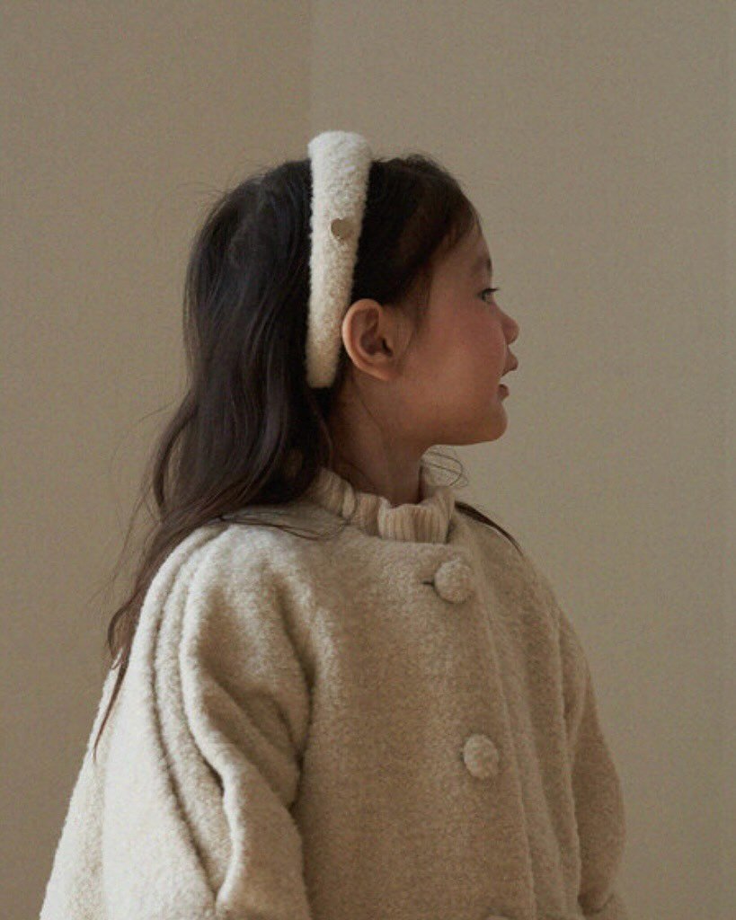 Photo by 마망블랑 mamanblanc on October 01, 2025. May be an image of 1 person, child, duffle coat, overcoat, barrette, cardigan and text.