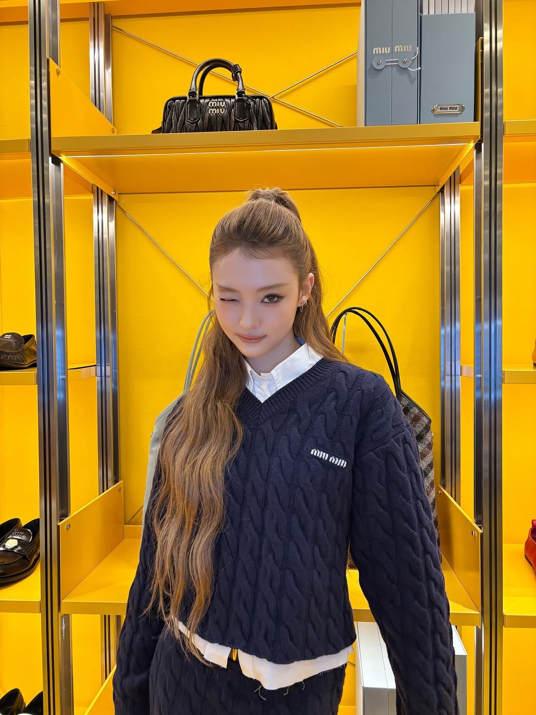 Photo shared by MEOVV on September 26, 2025 tagging @miumiu. May be an image of 1 person, duffle coat, display case and text.