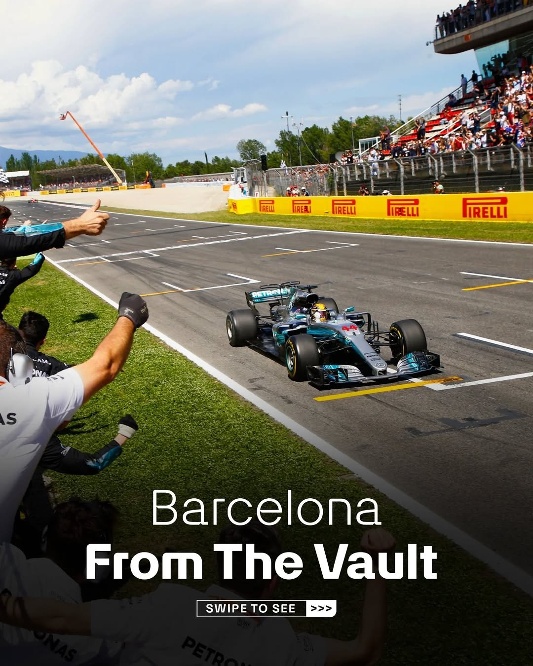 An image of Lewis Hamilton crossing the line to win the 2017 Spanish Grand Prix on the circuit de Barcelona-Catalunya. Mercedes staff and engingeers can be seen cheering in the left of shot. Text at the bottom of the shot reads 'Barcelona, From the Vault, Swipe to See'.