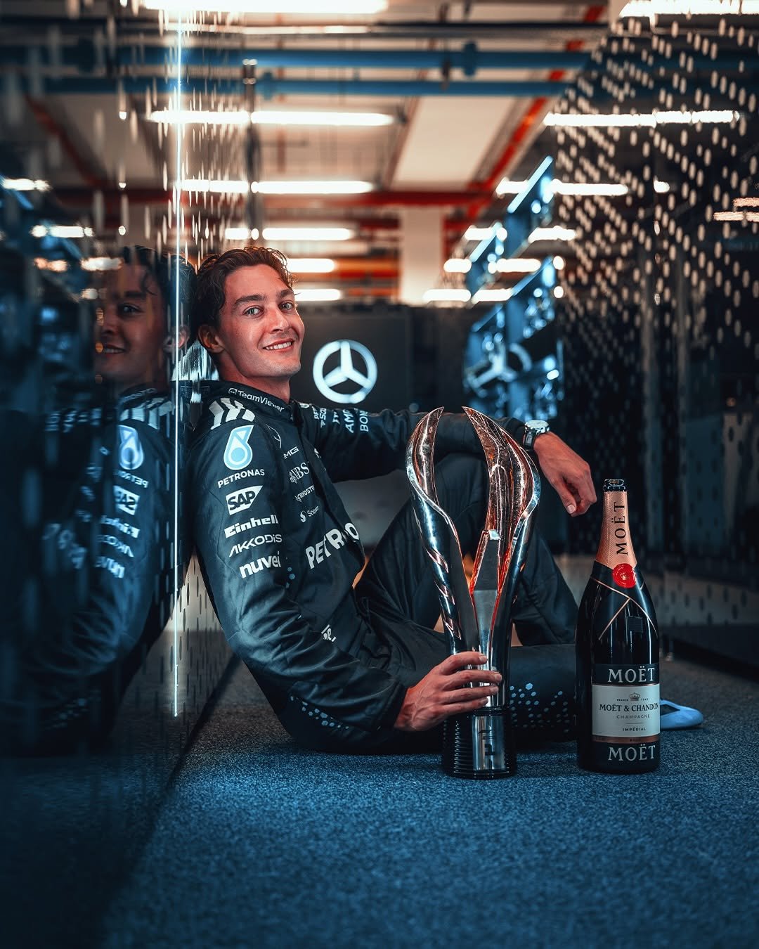 1. George Russell sat with trophy and champagne