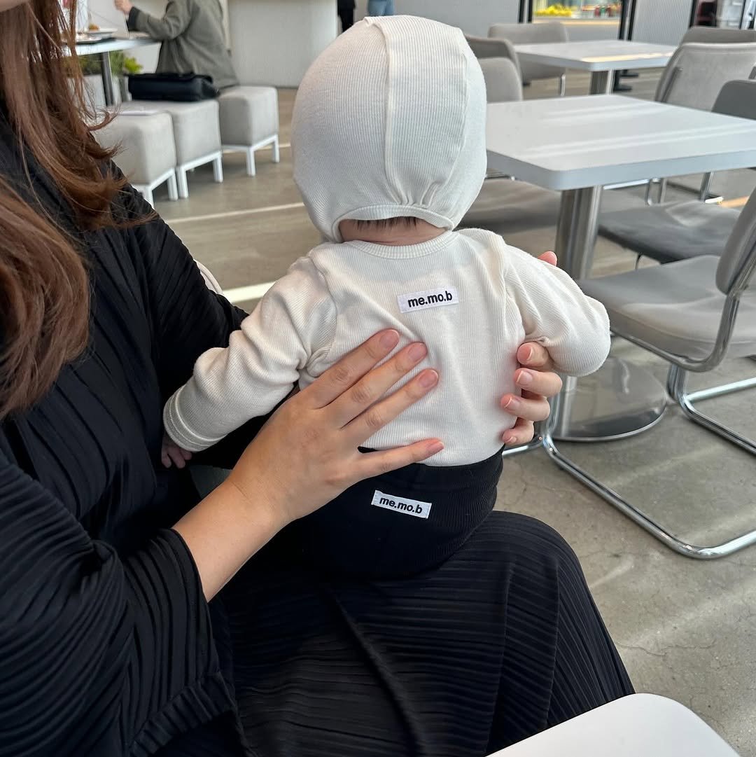 Photo by 메르모던(me.mo.b) on October 09, 2025. May be an image of 1 person, baby, hat, sling, diaper, baby shoes, cornflower and text.