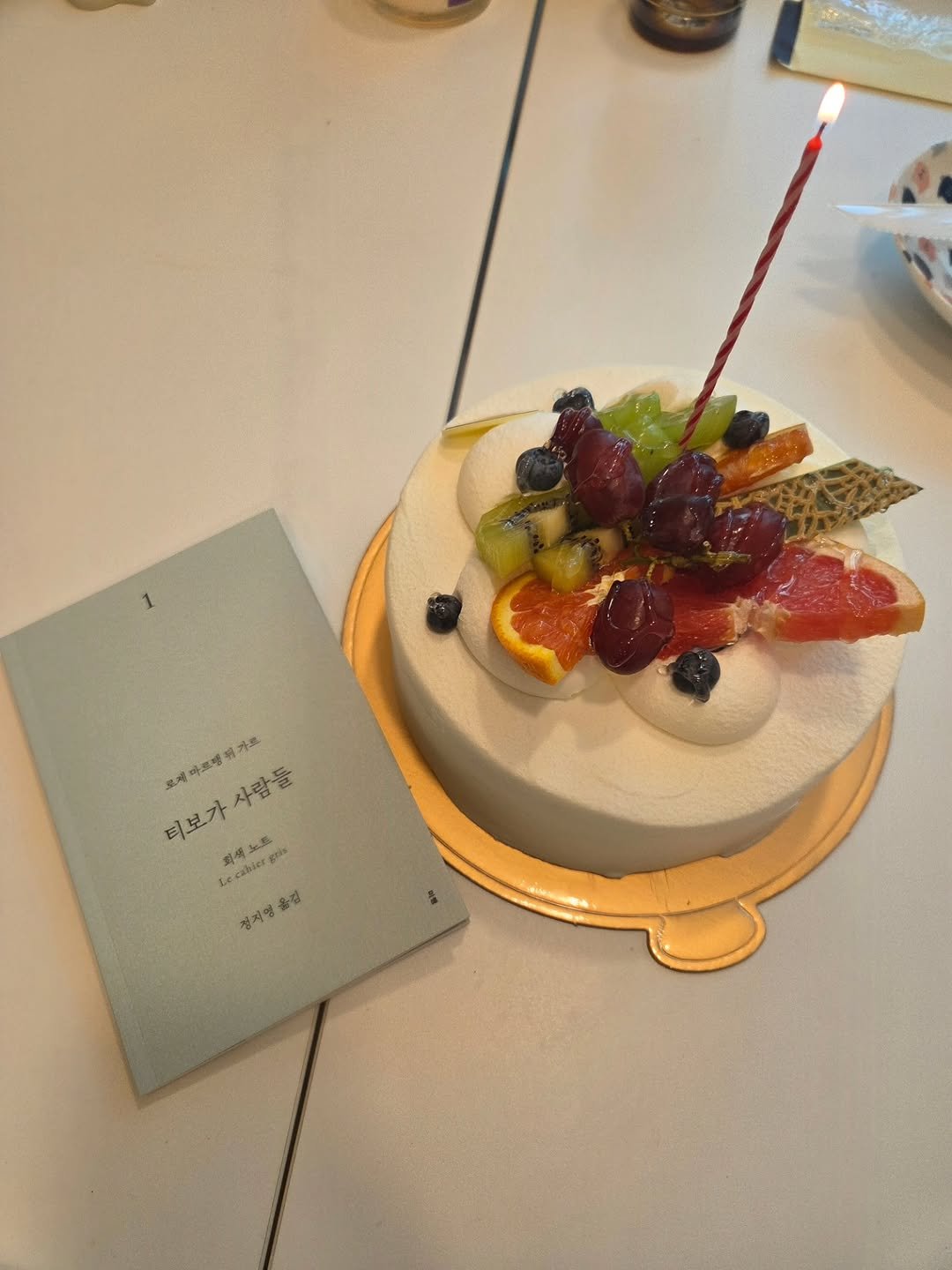 Photo shared by 문학전문출판사 미행 on October 26, 2025 tagging @springdaysbook. May be an image of ‎cake, fruitcake, candle and ‎text that says '‎용가로 요레 마르빵 크로레 사람들 티보가 최0목 티보가사람들 لكدت hier Kes Le 경지영 옮김‎'‎‎.